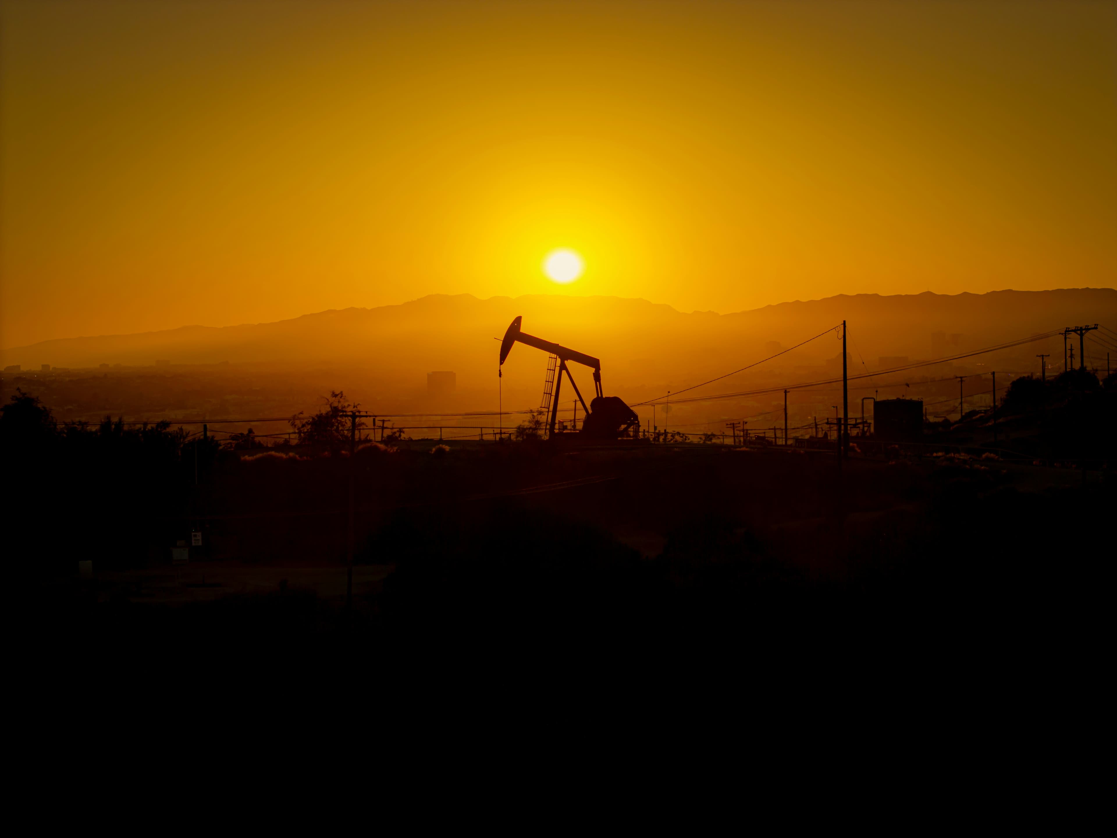 Pump jack silhouetted at sunset